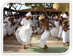 a group of people standing around each other in front of a building with white dresses and hats on