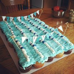 cupcakes with blue frosting and white decorations on top are arranged in the shape of a swimming pool