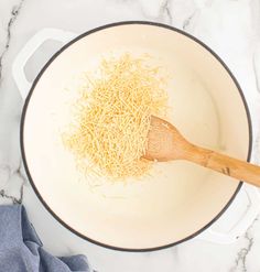 shredded cheese being cooked in a pan with a wooden spatula on the counter top