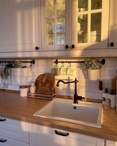 a kitchen with white cabinets and wooden counter tops, along with an old fashioned sink