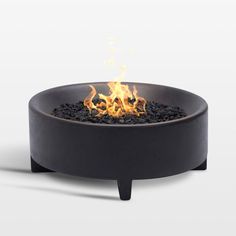 a black fire pit sitting on top of a white surface with flames coming out of it