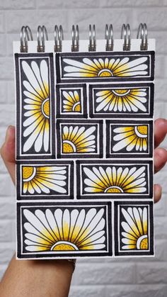 a hand holding up a small notebook with sunflowers on it