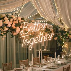 a lighted sign that says better together on top of a table with flowers and candles