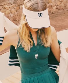 a woman in a green dress and white visor