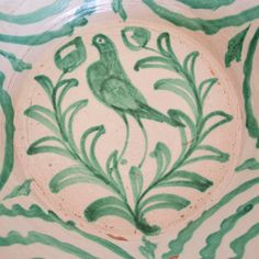 a green and white bowl with a bird painted on it