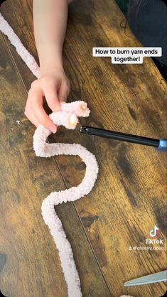 someone is writing out the word how to burn yarn ends together on a wooden table