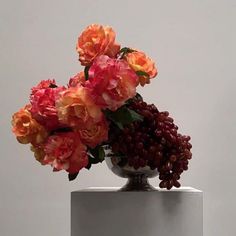 a vase filled with lots of flowers on top of a white tablecloth covered pedestal