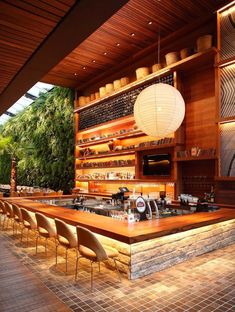 an outdoor bar with lots of chairs and lights hanging from the ceiling, along with wooden shelves