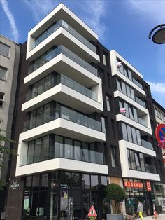 an apartment building with balconies on the top floor and glass windows at the bottom