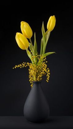 a black vase with yellow flowers in it