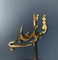 an arabic calligraphy sign hanging on the side of a blue wall with gold accents