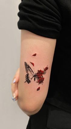 a woman with a tattoo on her arm has a butterfly and rose petals on it