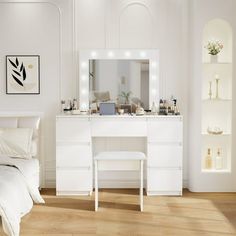 a bedroom with white furniture and lights on the dresser, bed and mirror in it