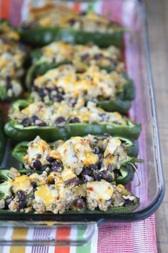 some green peppers with cheese and black olives in them on a plaid table cloth