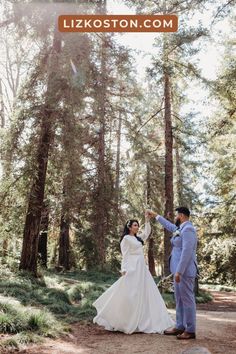 a bride and groom standing in the woods holding each other's hand with their arms