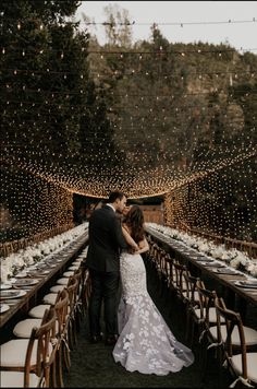 a bride and groom standing at the end of a long table