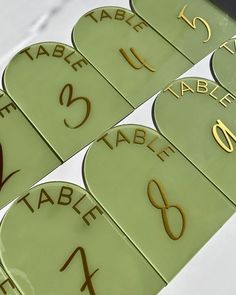 the table numbers are numbered in gold on green plates with black lettering that spell out their names