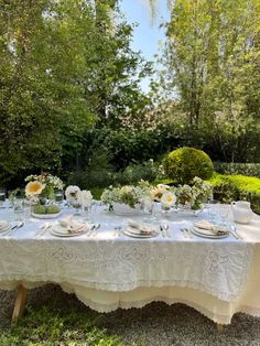 an outdoor table set with white linens and place settings for two people to sit at