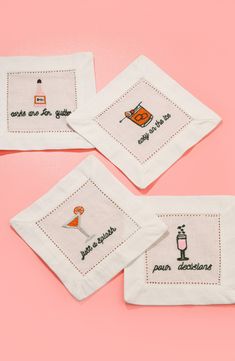 three embroidered cocktail napkins on a pink background