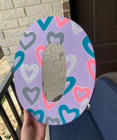 a person holding up a paper plate shaped like a letter with heart shapes on it