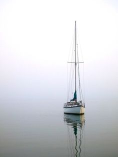 a sailboat floating in the water on a foggy day