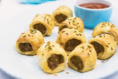 several sausage rolls on a plate with dipping sauce