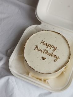 a birthday cake with the words happy birthday on it in a foam container sitting on a white sheet