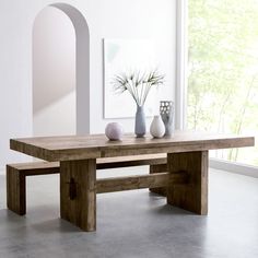 a wooden table with two vases on top of it next to a white wall