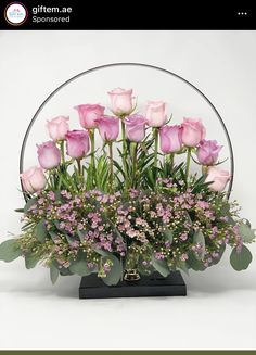 a vase with pink roses and greenery in it