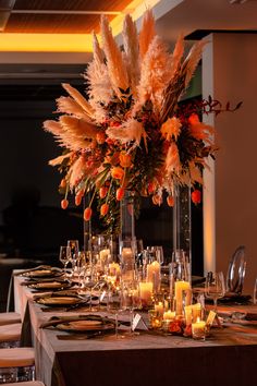 a long table with candles and flowers in tall glass vases on top of it