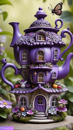 a purple teapot with a house on it and a butterfly flying over the top