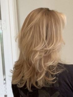 the back of a woman's head with long, blonde hair in front of a door