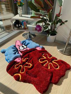 two rugs that are on the floor next to a potted plant in front of a window