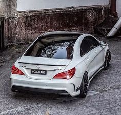 a white mercedes cla parked in front of an old building with graffiti on the walls