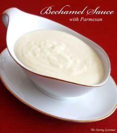 a white bowl filled with soup on top of a saucer next to a red tablecloth