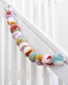 a crocheted garland on the side of a white rail in a baby's room