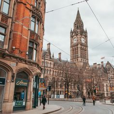 people are walking on the street in front of an old building with a clock tower