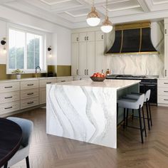 a large kitchen with marble counter tops and white cabinetry, along with two bar stools