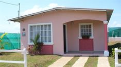 a small pink house with a white picket fence