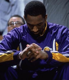 a man sitting down and looking at his cell phone while people watch from behind him