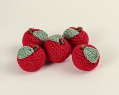 three crocheted apples with leaves on them are sitting next to each other in front of a white background