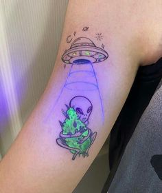 a person with a tattoo on their arm that has an alien in the sky above them