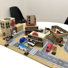 a table topped with toy cars and trucks on top of a road covered in cardboard