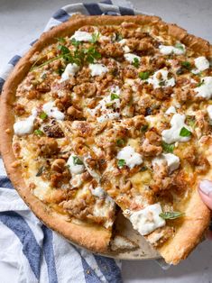 a person is holding a pizza with meat and cheese on it, ready to be eaten