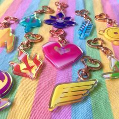 many different colored key chains are laying on a colorful blanket with an arrow, heart, and crown