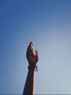 a hand reaching up into the sky to catch a kite