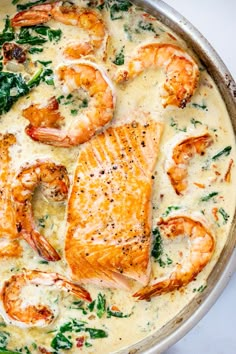 a skillet filled with shrimp and spinach covered in cheese on top of a white counter