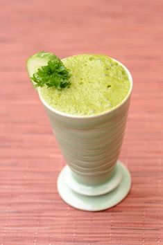 a green drink in a white cup on a table