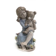 a ceramic figurine of a woman holding a baby in her arms on a white background