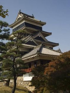 a tall building sitting on top of a lush green hillside next to a forest filled with trees